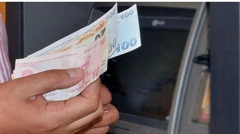 ATM önünde elinde Türk lirası banknotları tutan kişi